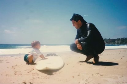 Young Jared Sislin over a surfboard at a Dana Point Beach