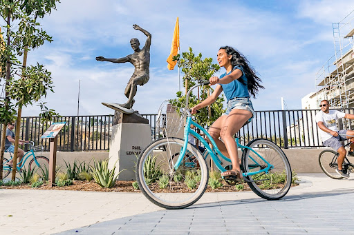 Girl riding bike in front of Dana Point Surfing Statue