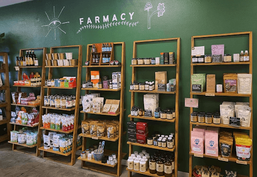 The Farmacy at Organic Tree: a wall with food, snacks, coffee, tea , herbs and an assortment of cvarious items on the shelves for sale at Organic Tree